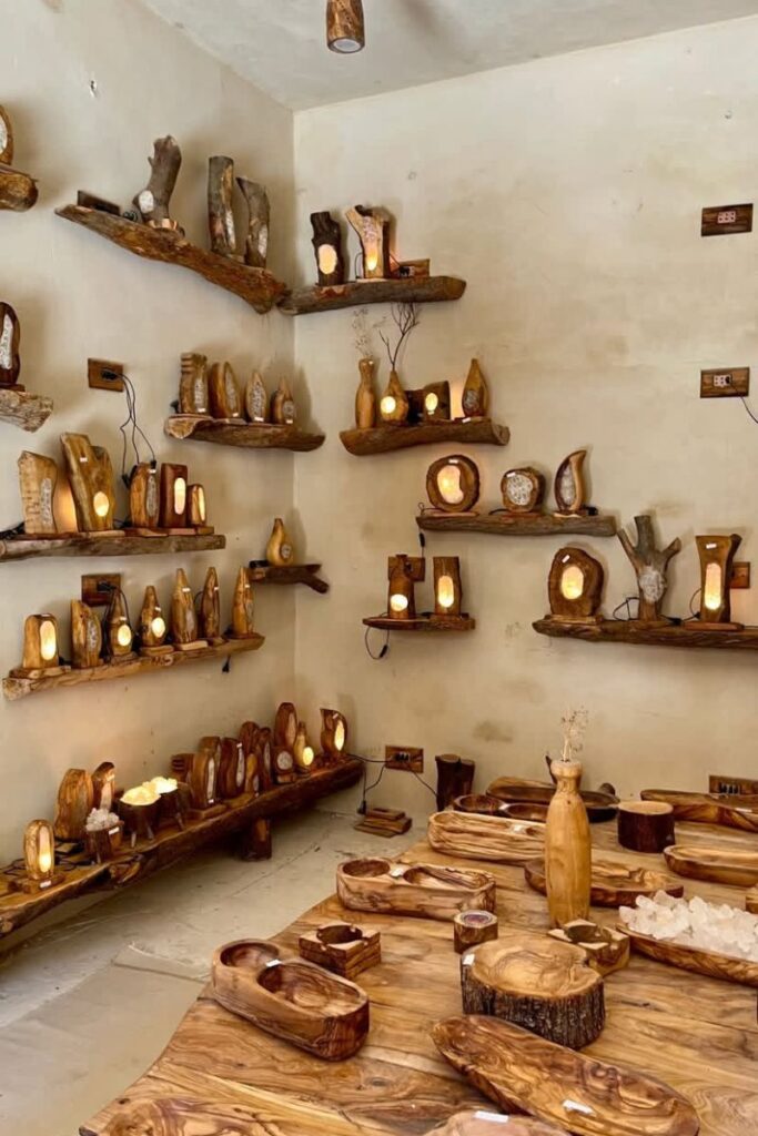 Interior of a Siwa shop filled with hand-carved wooden lamps and salt rock crafts, glowing warmly on wooden shelves—showcasing authentic artisan goods to discover during a Siwa Oasis trip.