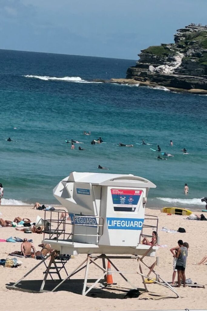 Lifeguard tower and surfers dotting the turquoise water of Bondi Beach—a safe and sunny spot for solo female travel in Australia, perfect for beach lovers seeking the best places for solo travel female in the US or abroad.