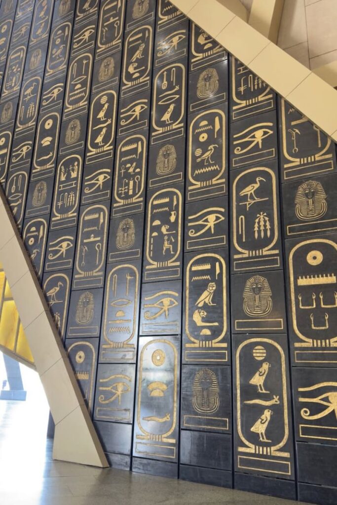 Large vertical panels of black and gold hieroglyphics line the wall inside Egypt's Grand Museum. A visually stunning stop for Americans traveling to Egypt and women wondering is it safe to travel to Egypt for cultural exploration.