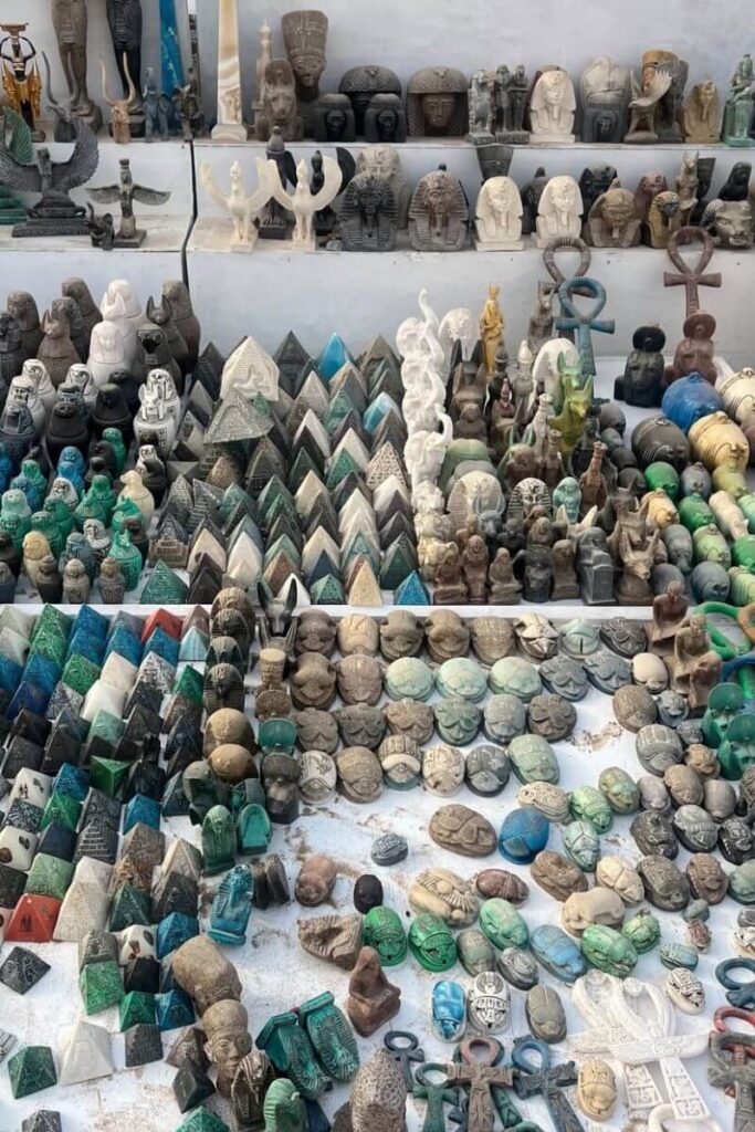 A dense display of stone souvenirs including miniature pyramids, scarabs, gods, and pharaoh busts in various colors and textures, neatly arranged in a market stall. This snapshot represents the full range of souvenirs in Egypt and makes for great suggestions for anyone exploring things to buy in Egypt—from king tut souvenirs to symbols of protection like the ankh and eye of Horus.