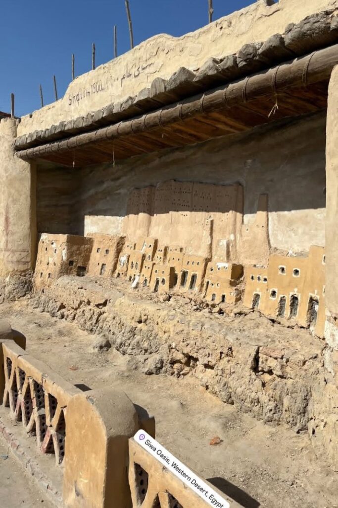 Clay model of Shali Fortress built into a mud wall, labeled “Shali in 1900,” located at Siwa Oasis, Western Desert, Egypt—depicting local history and one of the top things to do in Siwa.