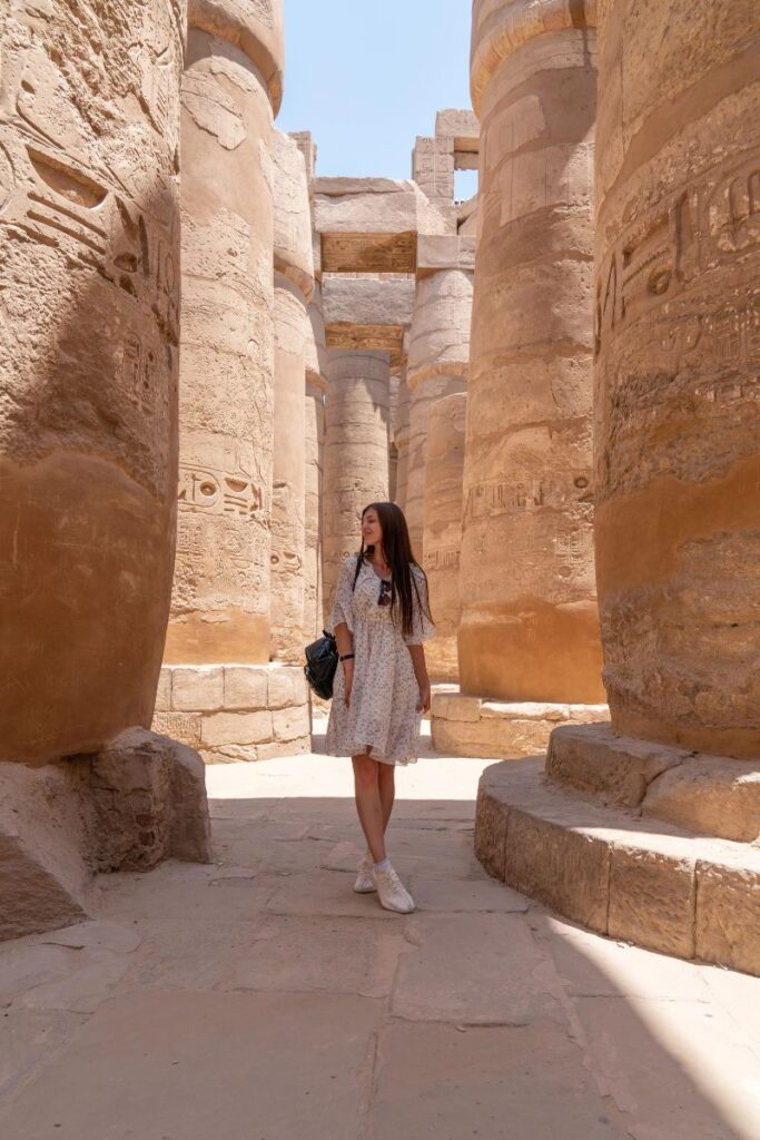 Solo female traveler strolls through towering stone columns covered in hieroglyphs at the Karnak Temple in Luxor. A dream destination for Egypt solo female travel and proof that traveling to Egypt as a woman can be both safe and inspiring.
