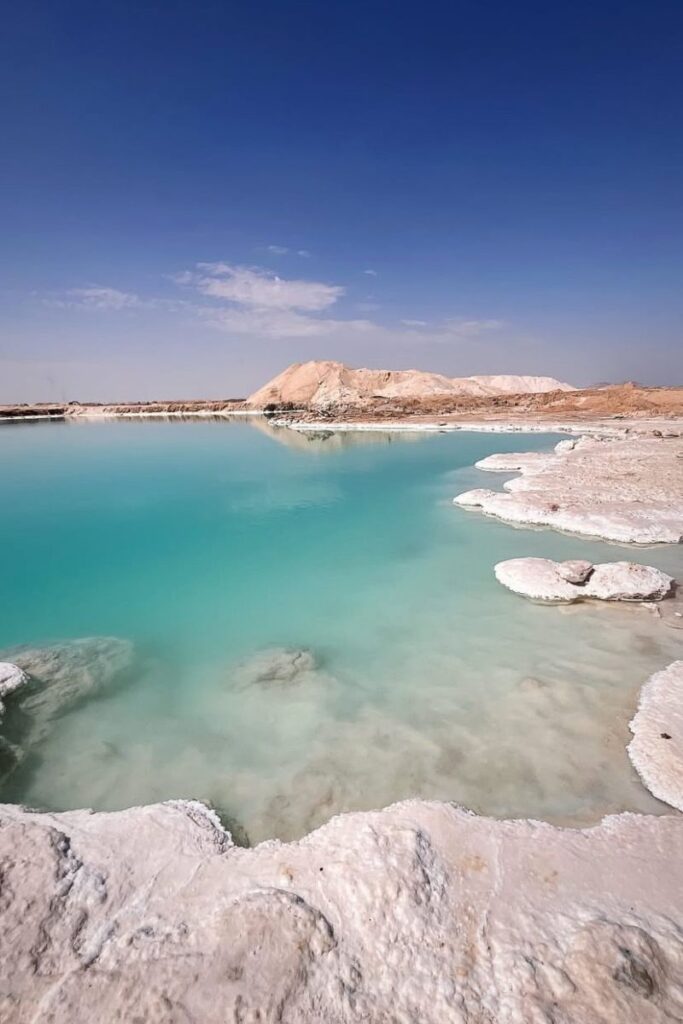 Turquoise waters and white salt formations create a surreal scene at the Siwa Oasis salt lakes. A unique natural stop on an off-the-beaten-path Egypt travel itinerary or for those backpacking in Egypt.