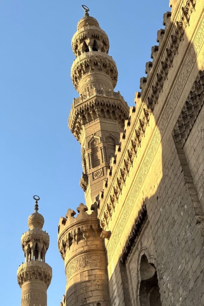 Close-up of detailed minarets and Islamic architecture glowing in the golden hour at the Mosque-Madrassa of Sultan Hassan in Cairo. A must-see on a 10 days in Egypt itinerary or any Egypt travel plans focused on Cairo.