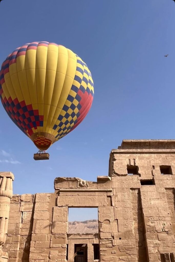 A colorful hot air balloon floats above the ancient ruins in Luxor against a blue sky. This view is a highlight of any 10 day itinerary Egypt or adventurous Egypt tour plan.
