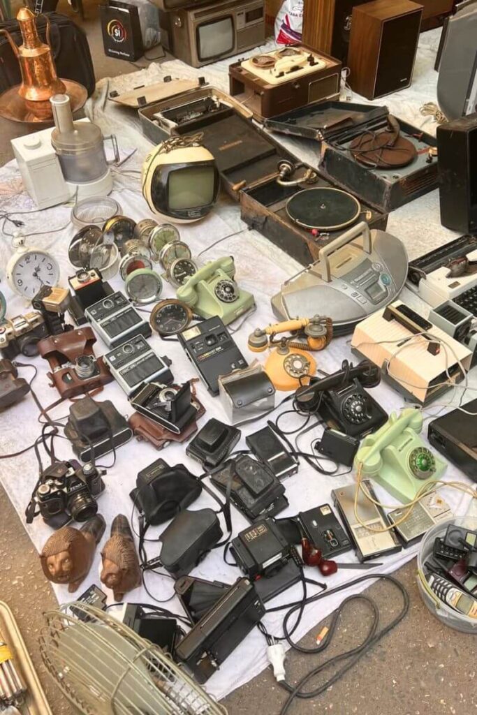A street stall in Hurghada selling retro cameras, rotary phones, vintage radios, and old clocks spread out on cloth. Perfect for vintage lovers and treasure hunters, this market experience is among the most unique things to do in Hurghada Egypt and adds character to your list of things to do in Hurghada city.