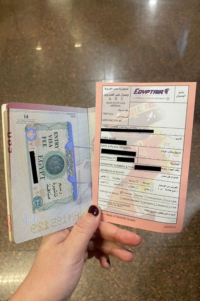 A tourist holds an open passport with an Egyptian visa sticker next to a filled-out arrival form from EgyptAir. Keep your documents organized with a travel wallet — a smart addition to your Egypt packing list and a non-negotiable on any packing for Egypt woman checklist.