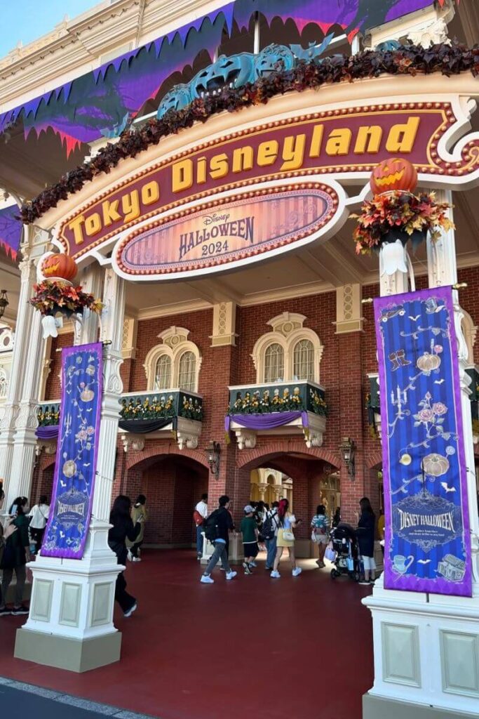 The entrance to Tokyo Disneyland decorated with jack-o’-lanterns, purple banners, and autumn leaves for Disney Halloween 2024, a fun place to visit for Halloween in Tokyo.