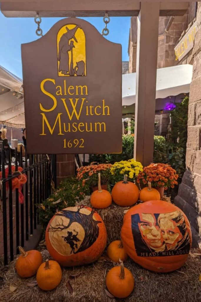 The Salem Witch Museum sign with pumpkins carved with witch and movie scenes, a must-see stop on a Halloween trip to Salem, Massachusetts.