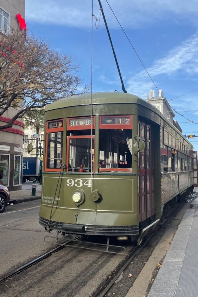 A historic green St. Charles streetcar in New Orleans, a city known for Halloween trips and spooky places to visit for Halloween in the US.