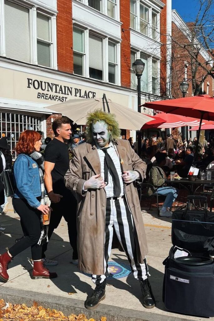 A performer dressed as Beetlejuice poses for photos during a Halloween festival, one of the fun places to go for Halloween on the East Coast.