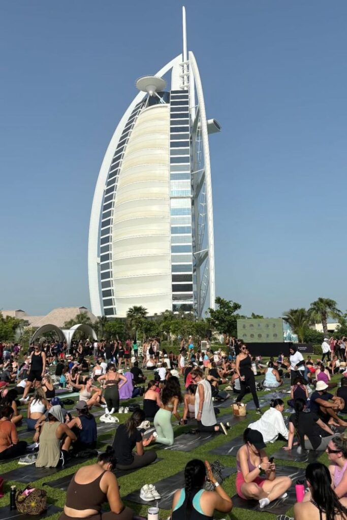 Hundreds of people participate in an outdoor yoga session on green grass in front of the iconic Burj Al Arab hotel in Dubai. With consistently hot weather in October, Dubai is one of the warmest destinations in October for wellness, luxury, and beachside retreats.