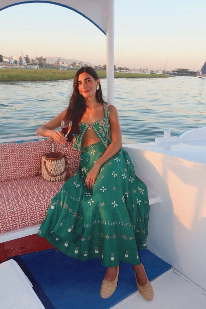 Woman in a green dress enjoying a drink while sitting on a boat during a Nile River cruise at sunset. A peaceful scene that fits beautifully into a 10 days Egypt itinerary or a relaxing itinerary in Egypt.