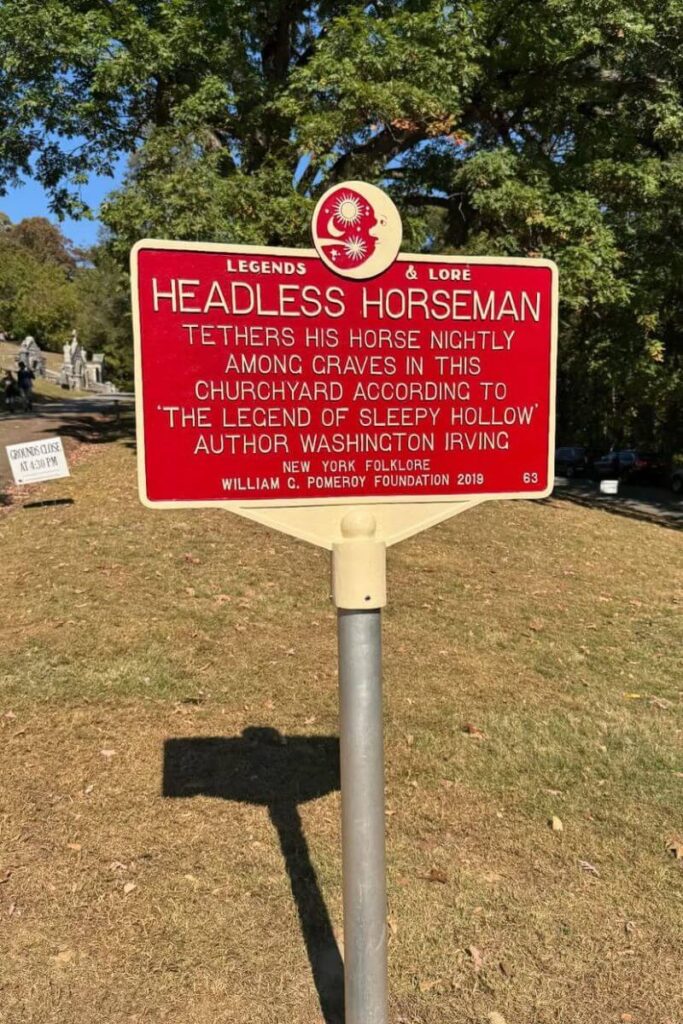 A red historic sign in Sleepy Hollow, New York, describing the Headless Horseman legend, making the area one of the most famous Halloween towns to visit on the East Coast.
