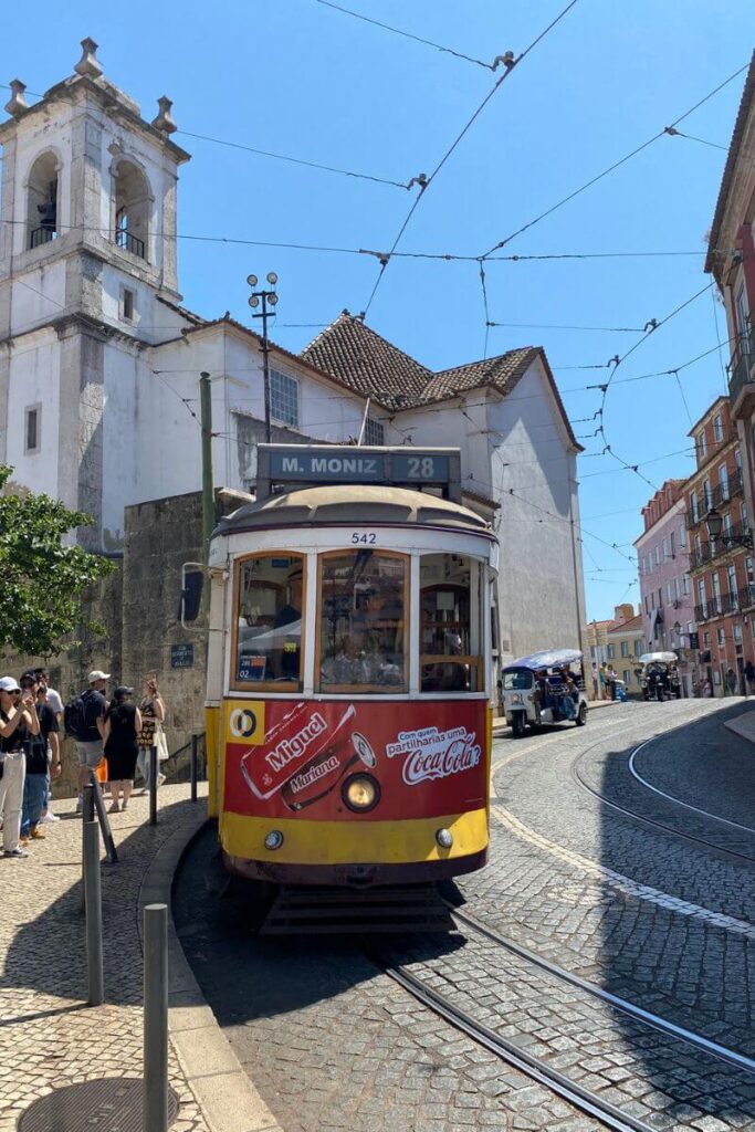 A classic yellow tram marked “M. Moniz 28” winds through the cobblestone streets of Lisbon’s historic Alfama neighborhood. With mild weather in October, Lisbon is one of the best European destinations in October for culture, warmth, and charm.