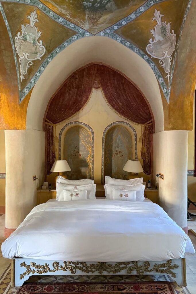 Luxurious and romantic hotel room in Egypt with an intricately painted vaulted ceiling, a plush bed, and detailed wall décor. Perfect for unforgettable experiences in Egypt and elegant stays for couples.