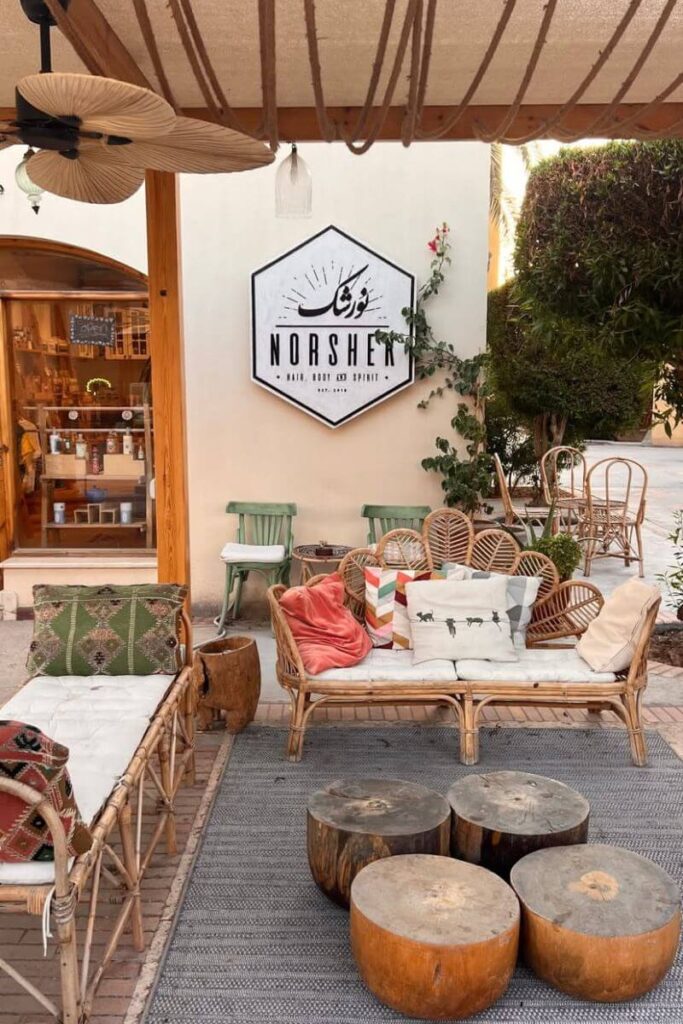 A cozy, bohemian outdoor lounge at Norshek in Hurghada, Egypt, featuring rattan chairs, colorful cushions, and rustic wooden stools under a canopy. This charming spot blends relaxation with local design and is a must-stop when exploring things to do in Hurghada city or enjoying unique things to do in Hurghada Egypt.