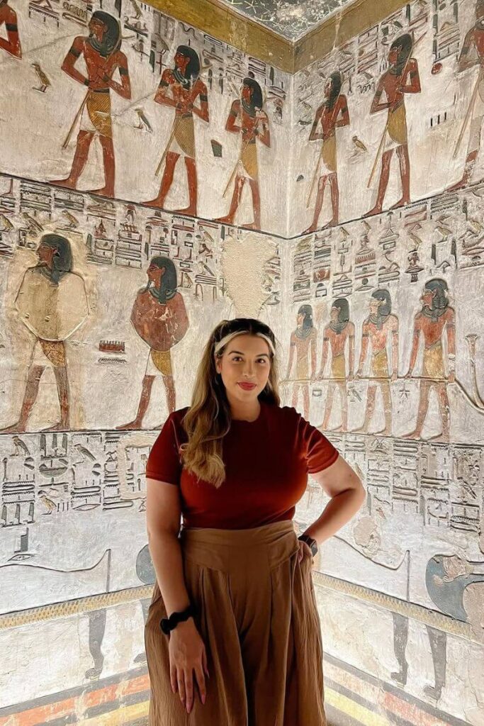 Tourist standing inside a richly decorated ancient tomb filled with hieroglyphics and murals of pharaohs. Exploring tombs like this is one of the most unforgettable experiences in Egypt and a top Egypt bucket list item.