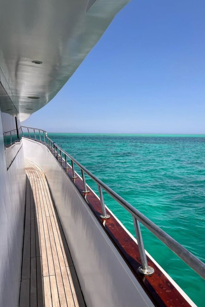 View from the side of a white yacht cruising through crystal-clear turquoise water off the coast of Hurghada. Boat excursions like this are among the most popular Hurghada activities and a must-do for exploring the best places to go in Hurghada by sea.