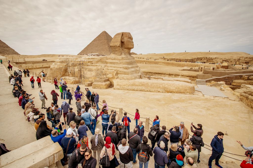 Tourists gathered at the base of the Sphinx with the pyramids in the background – an iconic stop for any Egypt travel blog, featuring tips for visiting pyramids in Egypt and navigating popular tourist areas.