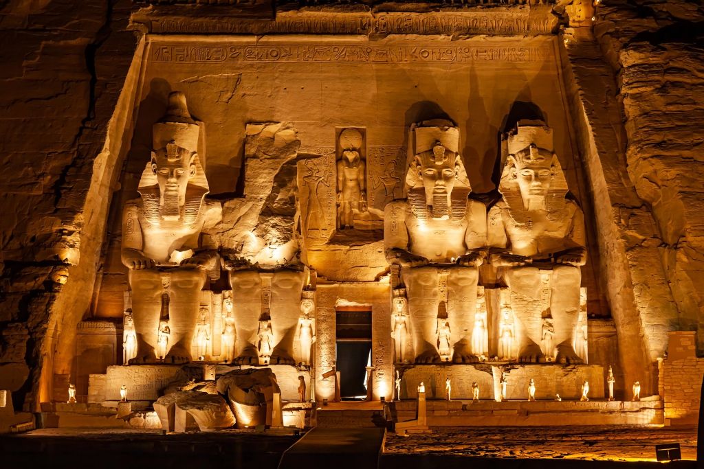 Abu Simbel glowing with golden light at night, showcasing its colossal statues and intricate carvings. A nighttime visit is a must-do in Egypt and one of the most unforgettable experiences in Egypt.