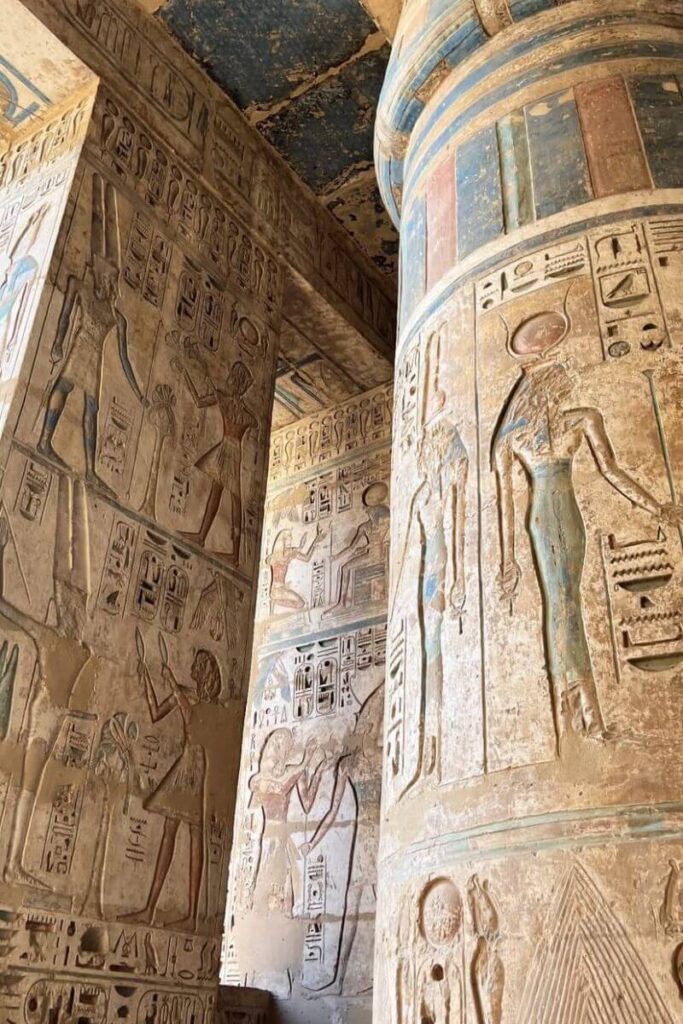 Intricate hieroglyphics and painted carvings cover massive stone columns inside an ancient Egyptian temple. Egypt is among the hottest holiday destinations in October, ideal for travelers seeking warm weather and historical exploration.
