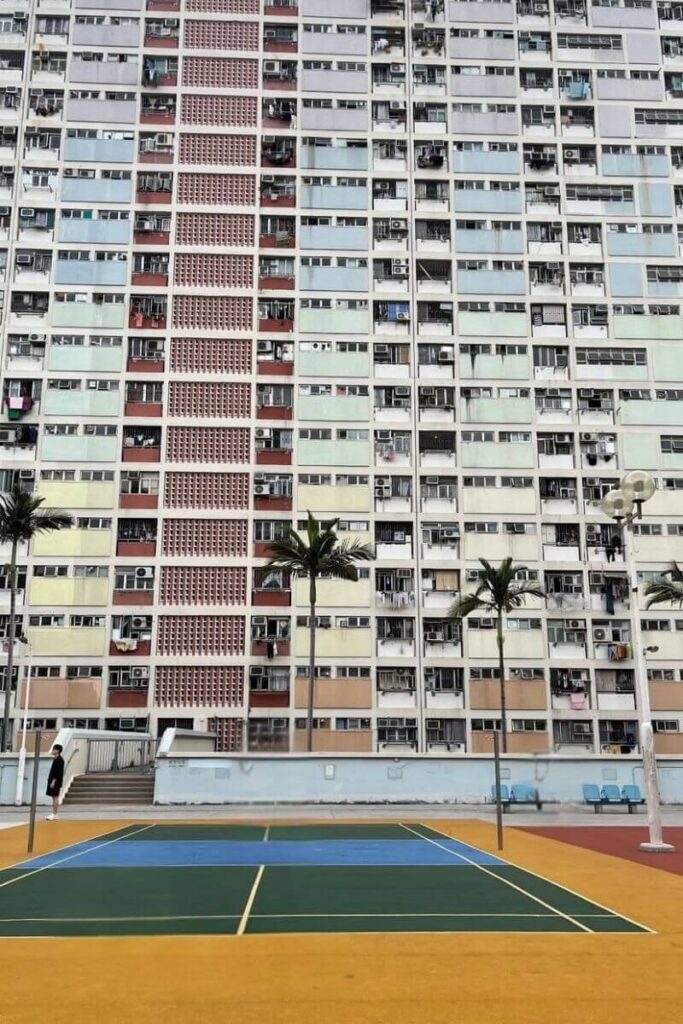 A colorful outdoor basketball court set against the pastel rainbow facade of the Choi Hung Estate, a popular photo spot. Visiting this vibrant housing complex is one of the most unique things to do in Hong Kong and a must for those seeking cool things to do in Hong Kong for Instagram.