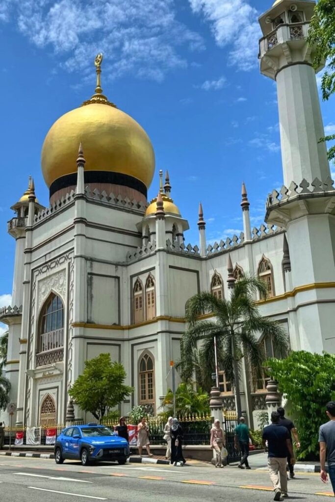 The majestic Sultan Mosque in Kampong Glam stands under a bright blue sky, with its gold domes and minarets shining above the street below. This historic landmark is one of the most culturally significant attractions in Singapore and perfect for travelers seeking hidden gems in Singapore.