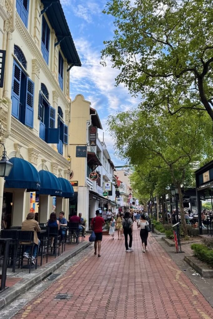 A vibrant pedestrian street lined with historic buildings, shaded trees, and al fresco dining options on a brick-paved walkway. This is one of the hidden gems in Singapore and a relaxed alternative for those exploring local eateries and cultural Singapore things to do.