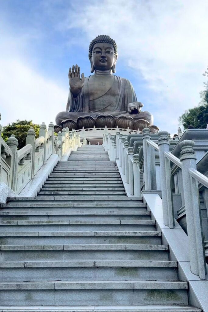 The Tian Tan Buddha statue on Lantau Island viewed from the long staircase leading up to it. Visiting the Big Buddha is a top Hong Kong travel tip and one of the most meaningful cultural stops in any Hong Kong itinerary.