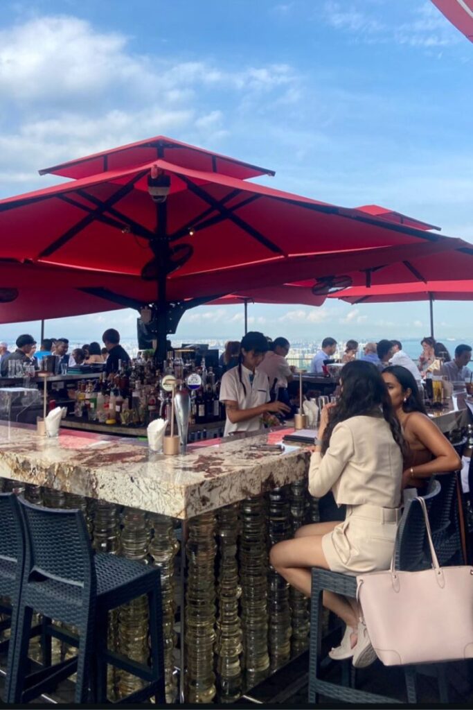 A lively rooftop bar with red umbrellas, cocktails, and sweeping views over Singapore. An unmissable stop for those deciding between Singapore vs Hong Kong nightlife and dining.