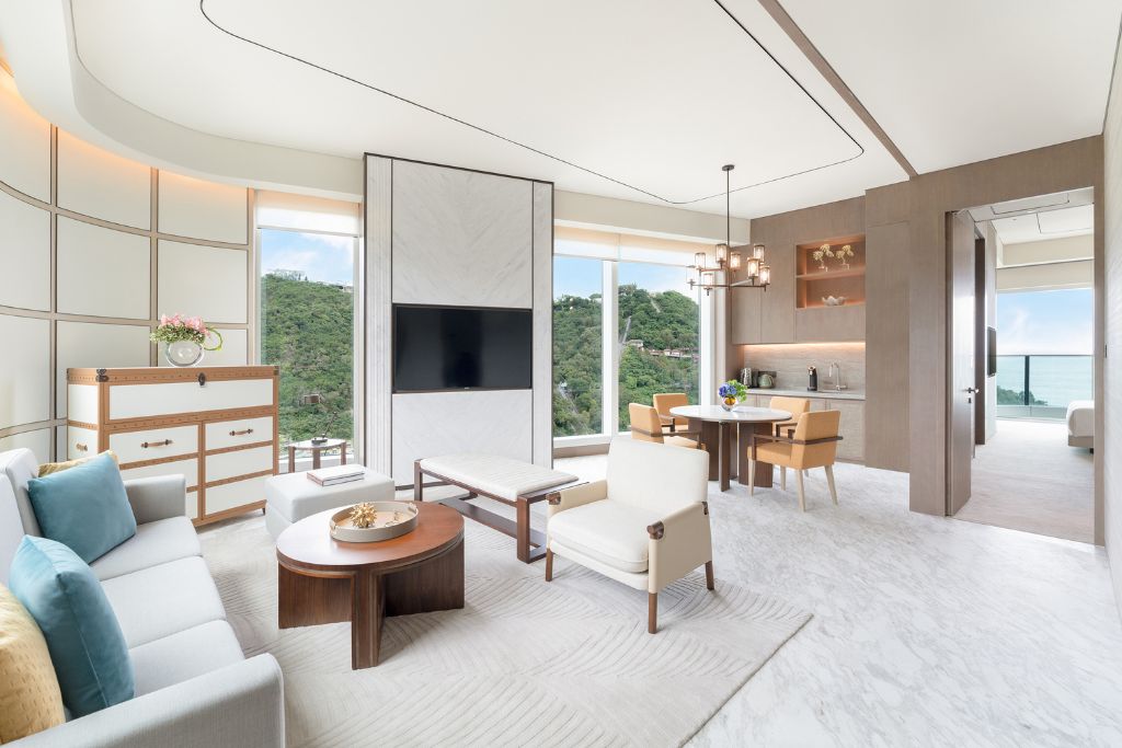 Elegant modern hotel suite in Hong Kong with large windows overlooking green hills and the ocean. Choosing accommodations with scenic views is one of the best tips for Hong Kong travel comfort.