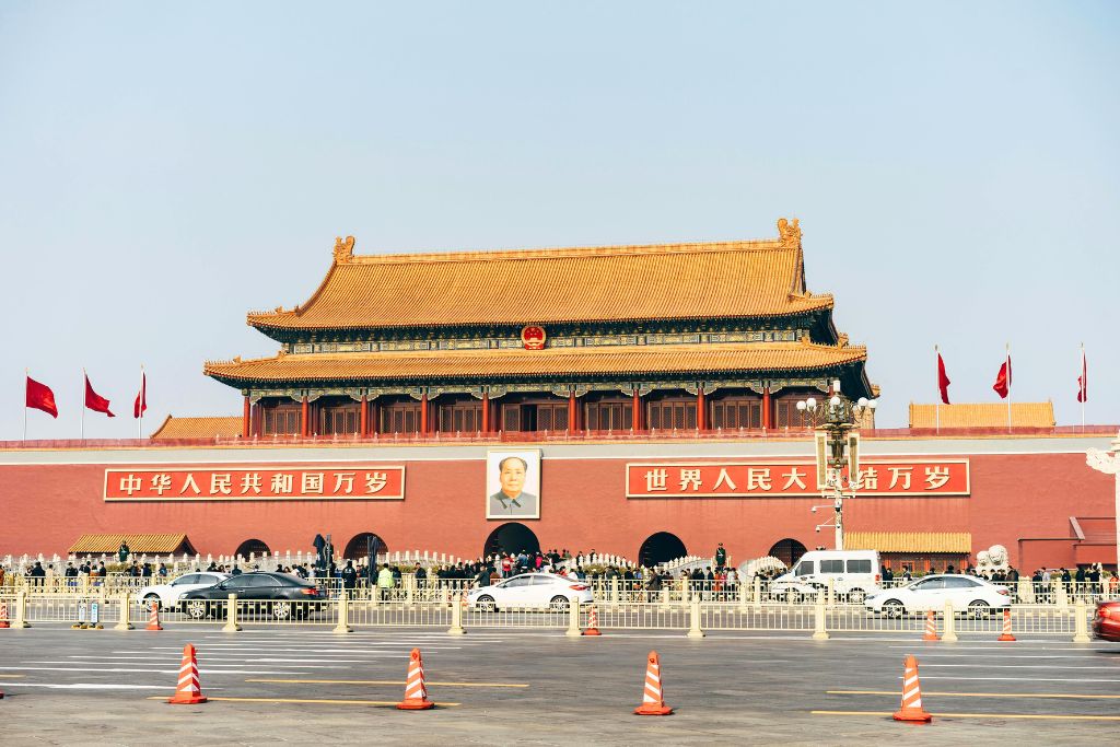 The grand Tiananmen Gate in Beijing with red walls, golden roofs, and a portrait of Mao Zedong. While not in Hong Kong, knowing travel advisory distinctions is key for those planning Asia trips and guides.