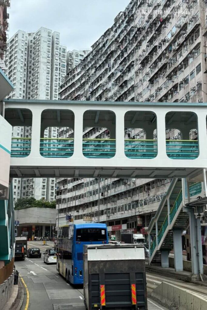 High-rise residential blocks with narrow balconies in Hong Kong, connected by a pedestrian sky bridge. A striking urban contrast in the Hong Kong vs Singapore lifestyle debate.