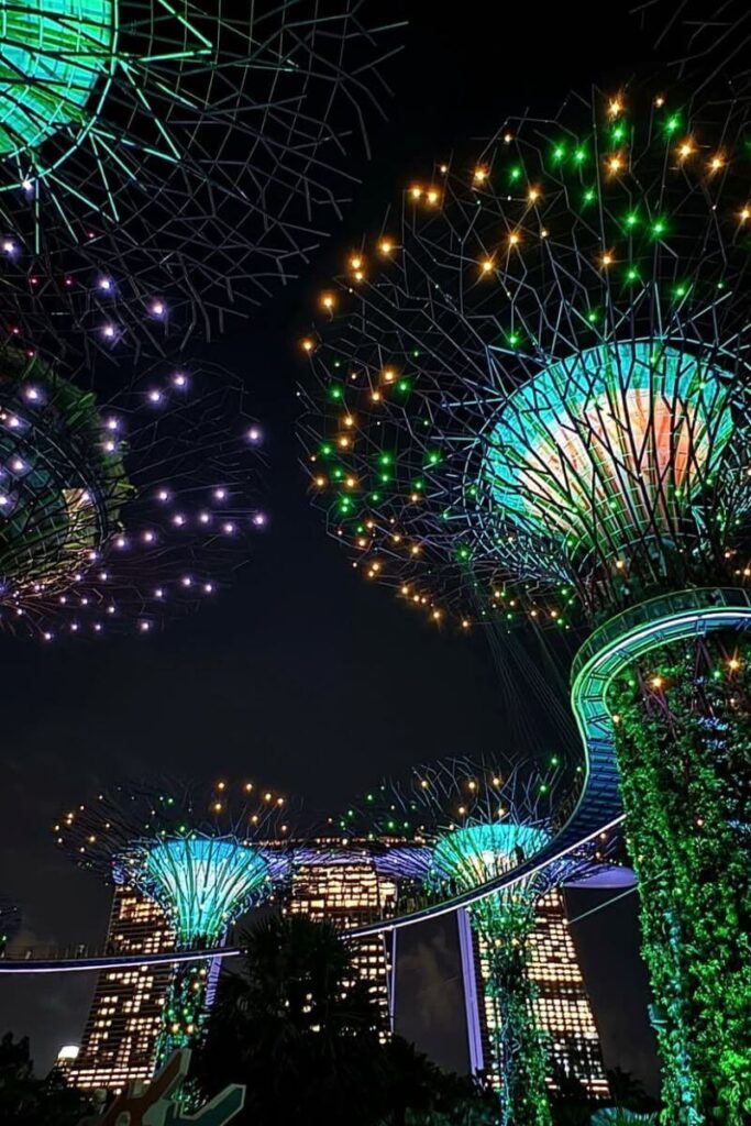 The Supertree Grove at Gardens by the Bay lit up in green, blue, and purple during its nightly Garden Rhapsody show. This vibrant display is one of the most memorable things to do in Singapore at night and an unmissable attraction for first-time visitors.