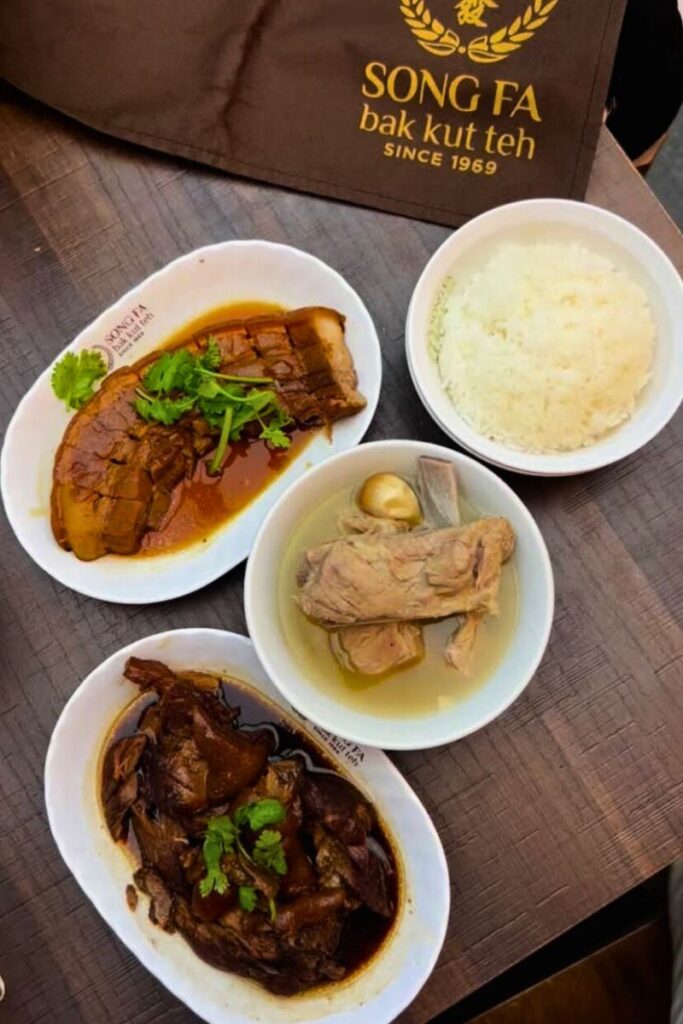Flat lay of a traditional bak kut teh meal at Song Fa, featuring pork rib soup, braised meats, and white rice in white bowls. Tasting this hearty dish is one of the top food-focused activities in Singapore and a must-try for fans of authentic local cuisine.