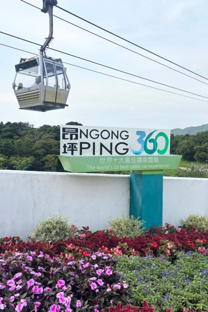 A cable car glides above greenery near the Ngong Ping 360 station, known as one of the world’s top cable car rides. Taking this ride is one of the best Hong Kong travel tips for visiting Lantau Island.