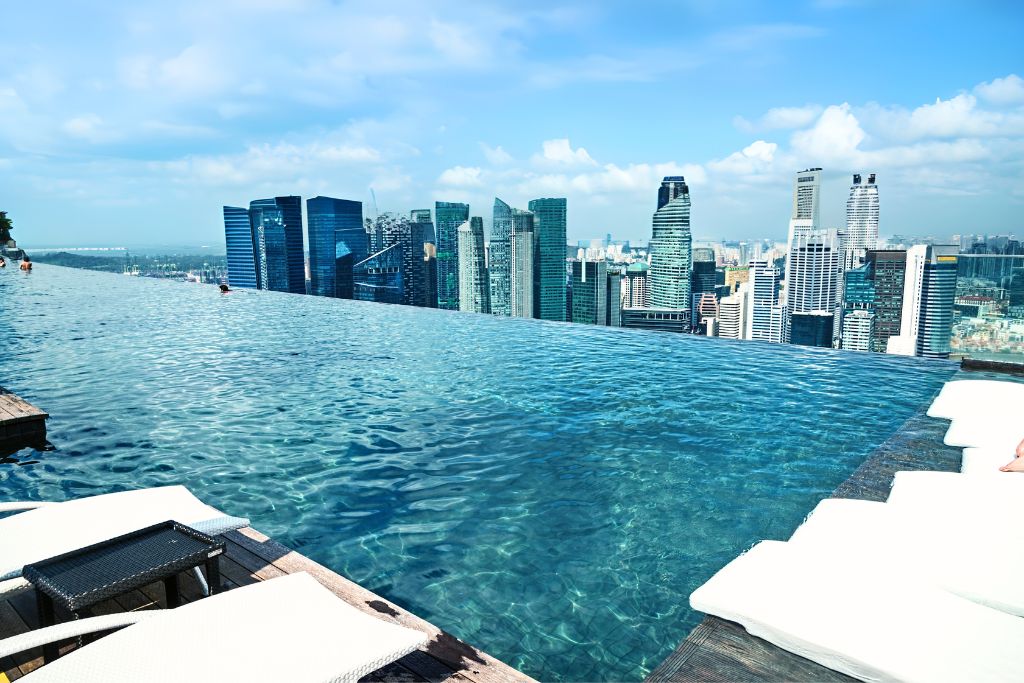 The rooftop infinity pool at Marina Bay Sands offering sweeping views of the modern Singapore skyline under blue skies. A luxurious bucket list experience and one of the most iconic Singapore attractions, perfect for travelers exploring unique things to do in Singapore.