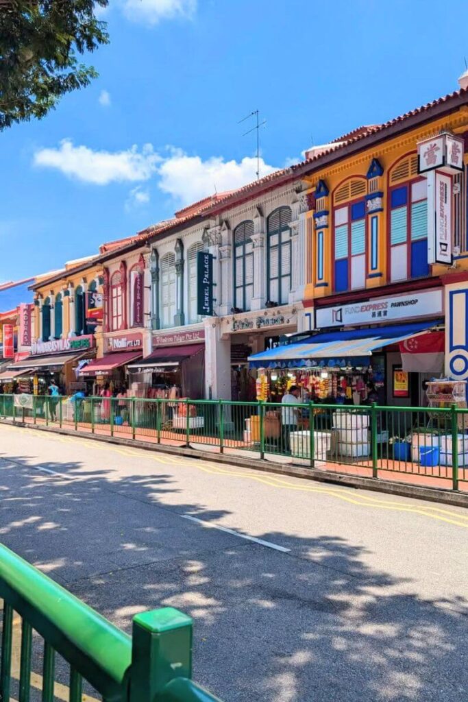 A row of vibrant, colonial-era shophouses in Little India, Singapore, each painted in bold colors and filled with local shops and businesses. Strolling through this lively area is one of the best cultural things to do in Singapore and a great place to shop for souvenirs.