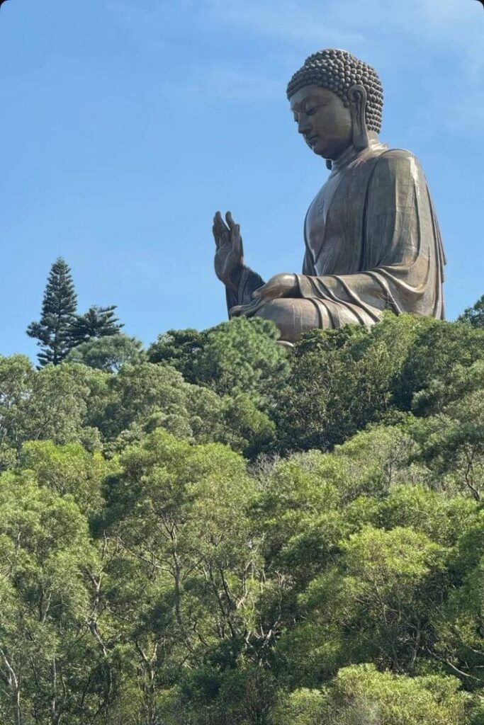Close-up shot of the Tian Tian Buddha Hong Kong rising above lush greenery under a clear blue sky. This serene image showcases why the Big Buddha in Hong Kong is a top pilgrimage site and a must-see on a Lantau Island itinerary.