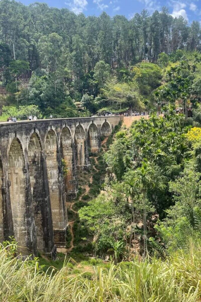 The iconic Nine Arches Bridge stretches through lush tropical greenery under clear skies, a scenic spot for travelers chasing warm destinations in December and tropical winter trips.