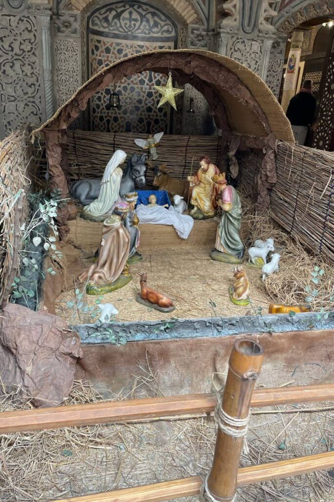 A detailed nativity display with figurines of Mary, Joseph, and baby Jesus beneath a rustic shelter, celebrating the holiday spirit in warm places to go in December.