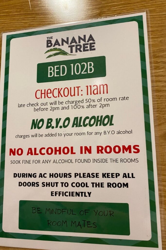 A printed sign from The Banana Tree Hostel listing checkout times, alcohol restrictions, and AC policies. It highlights important hostel rules and regulations and is a must-read for anyone learning hostel etiquette before checking in.