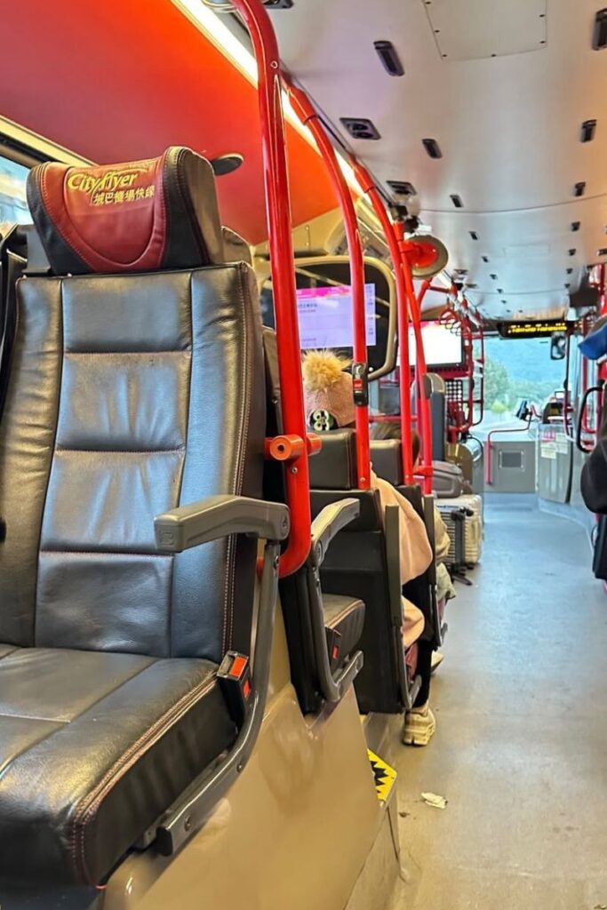 Interior of a Cityflyer bus with red railings and leather seats, one of the convenient transport options to reach the Buddha in HK.