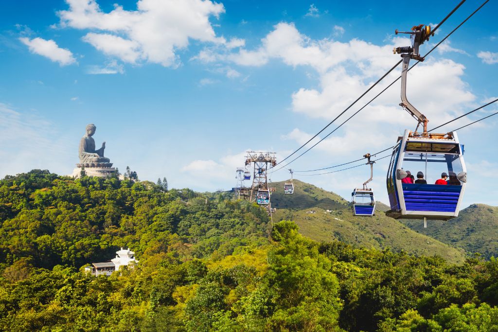 Panoramic view of the Ngong Ping 360 cable cars leading toward the HK Big Buddha on a forested hilltop. This ride offers stunning views of Lantau Island and is one of the best ways to reach the Big Buddha in Hong Kong.
