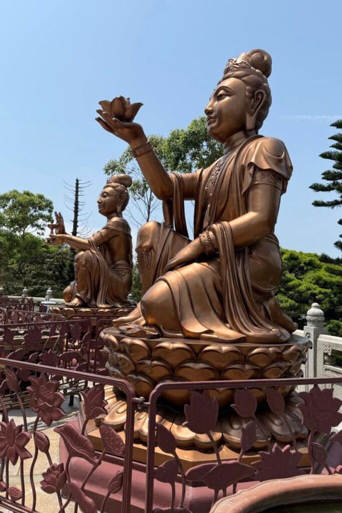 Bronze offering statues holding lotus flowers sit near the Tian Tian Buddha Hong Kong. These sacred figures highlight the spiritual side of the Hong Kong Big Buddha.