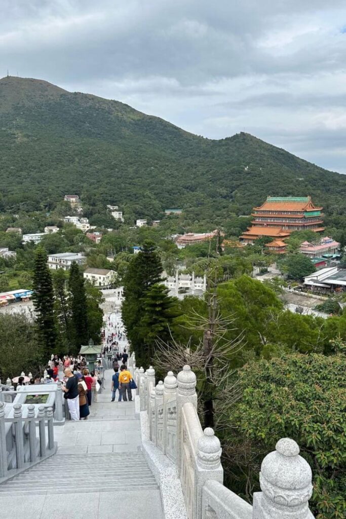View from the stairs leading down from the Big Buddha Hong Kong, with Po Lin Monastery and Lantau Island’s lush hills in the distance.