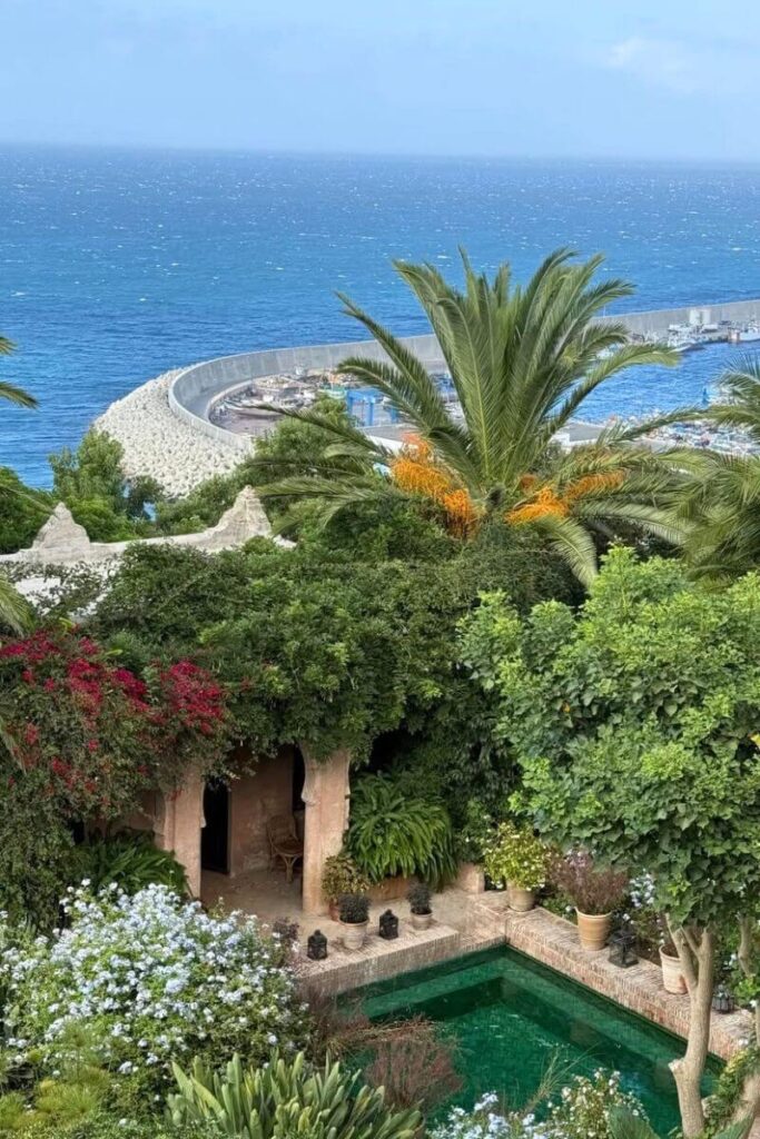 A lush Mediterranean-style terrace overlooking the sea with palm trees and bright flowers, a peaceful hideaway perfect for warm European destinations in December and sunny winter getaways.