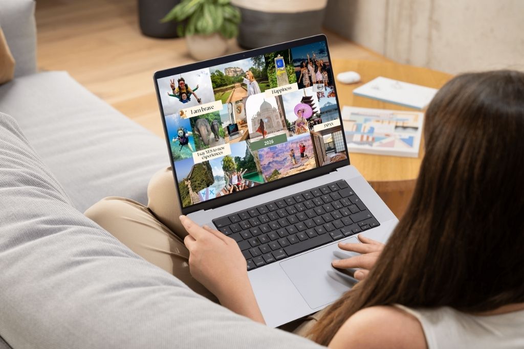 A woman works on a laptop showing a digital collage of dream destinations, perfect for my travel vision board inspiration and travel vision board template ideas for 2025.